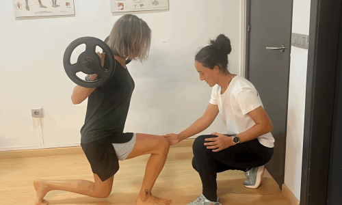 Fisioterapeuta assistint una pacient mentre fa exercicis de força amb peses.